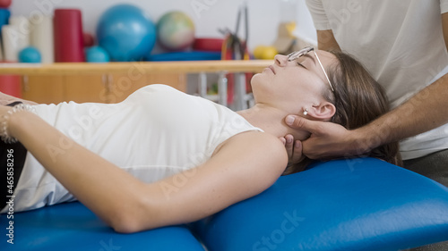 Man hands doing manual joint neck stretching and giving a neck massage to a young Caucasian woman