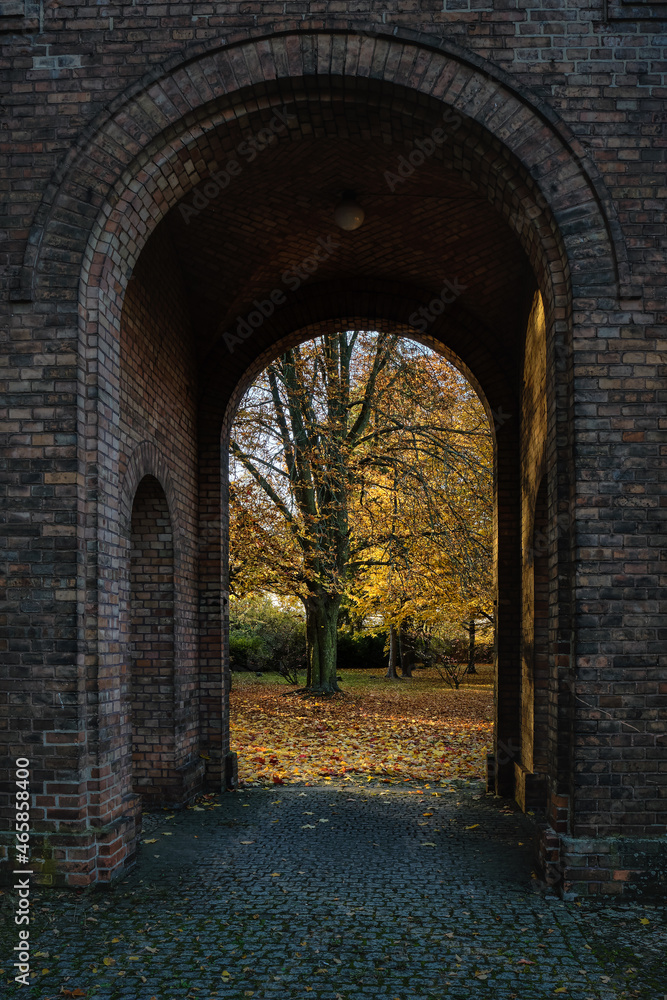 Blick durch ein Tor des Säulengangs auf die Herbstbäume im historischen Berliner 