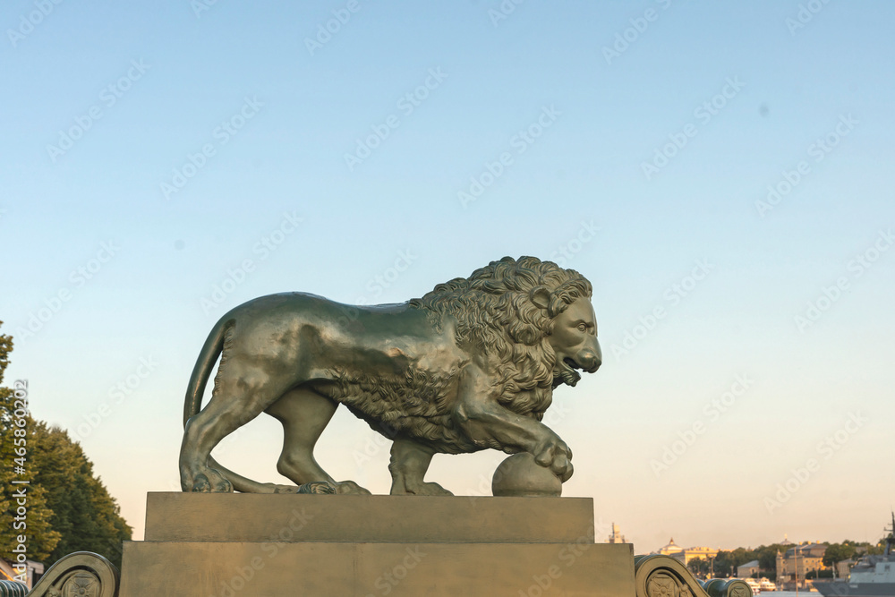 stone sculpture of a lion putting his paw on a ball on the embankment of the Neva River in St. Petersburg, Russia. The concept of strength, power.