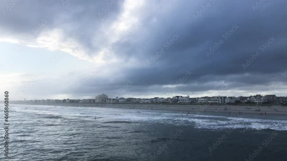 Dark clouds over mostly deserted beach seen from the ocean Dark clouds over mostly deserted beach seen from the ocean
