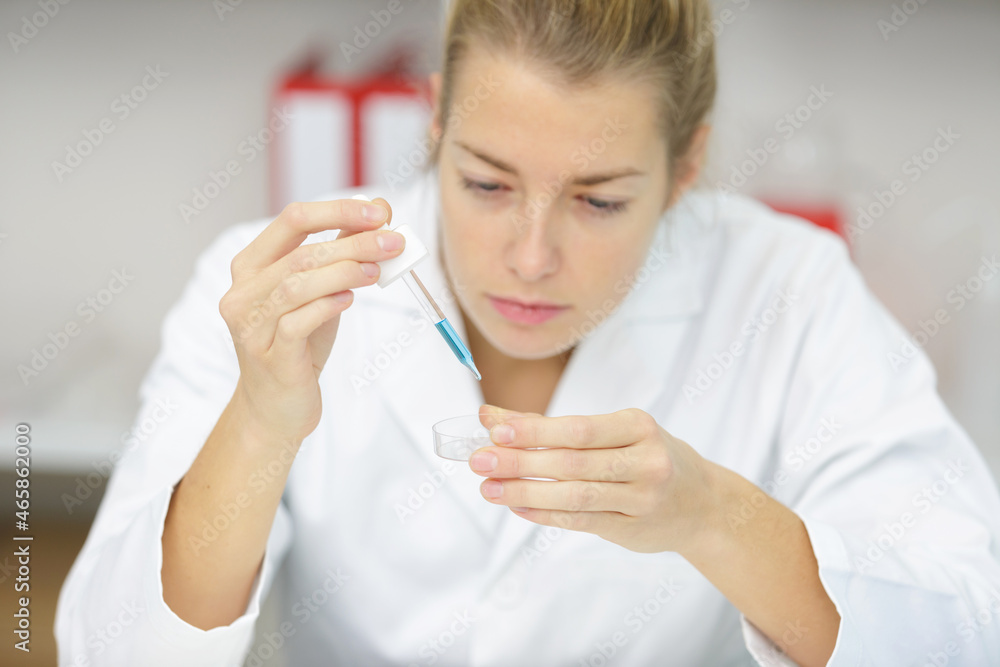 a lab technician examines the liquid in a pipette a lab technician examines the liquid in a pipette