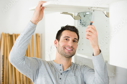 screwing the furniture hinge leaf to the white cabinet