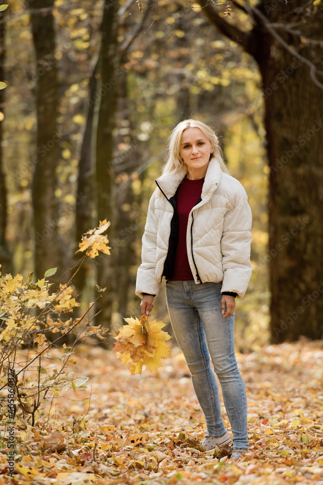 Portrait of a young blonde woman in the autumn forest, with a bouquet of yellow leaves in her hands. Portrait of a young blonde woman in the autumn forest, with a bouquet of yellow leaves in her hands.