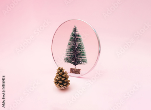 Pine cone look in to mirror and see new year green snow tree. Pink pastel background. Minimal holiday design and concept.