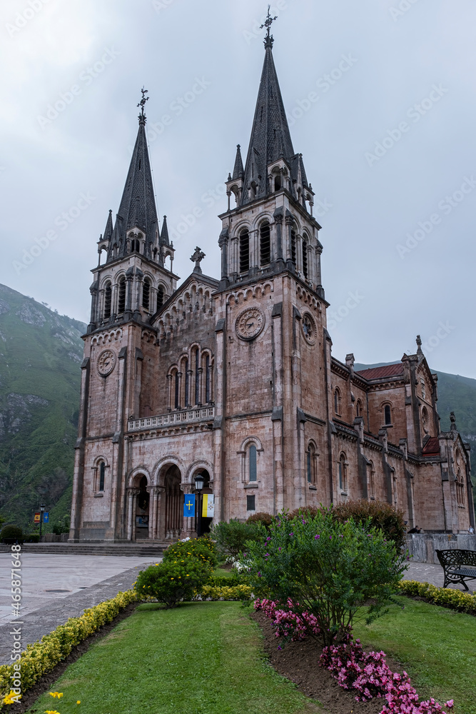 Main facade of the Sanctuary of the Virgin of Covadonga, Asturias, Spain, with its two tall bell towers and its characteristic reddish stone, vertical