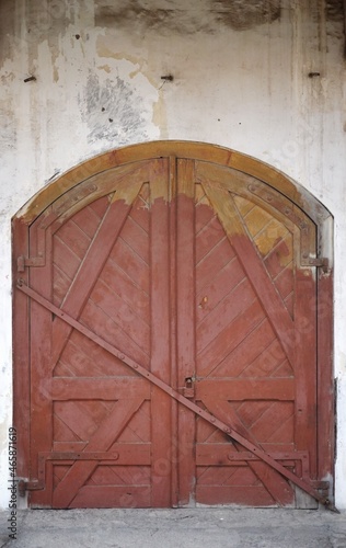 Wooden double barn door with rounded corners. Wooden plank door with forged metal parts