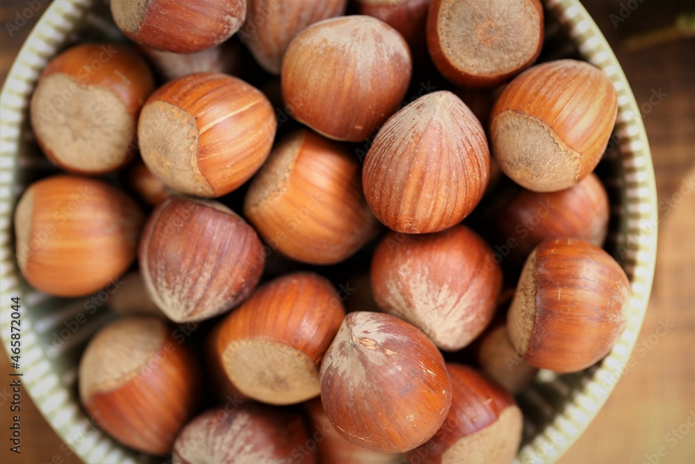 ripe hazelnuts close-up in a round cup on a wooden table.Vegetable protein source. Healthy fats. Farmed organic ripe hazelnuts ripe hazelnuts close-up in a round cup on a wooden table.Vegetable protein source. Healthy fats. Farmed organic ripe hazelnuts