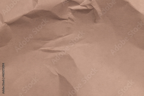 Brown crumpled wrapping paper close-up with a gradient of light and shadow