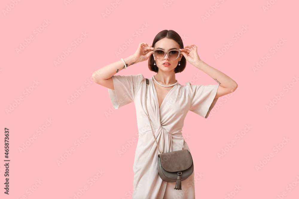 Young woman wearing stylish sunglasses and jewelry on color background