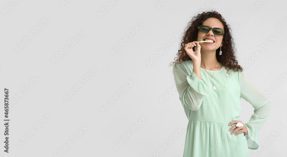 Cool African-American woman with chewing gum on light background Cool African-American woman with chewing gum on light background
