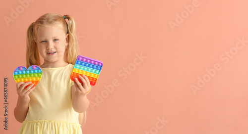 Pretty girl holding different pop it fidget toys on color background
