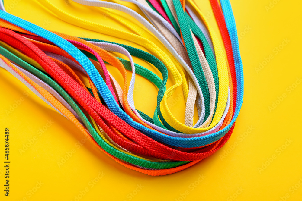 Many different shoe laces on yellow background, closeup