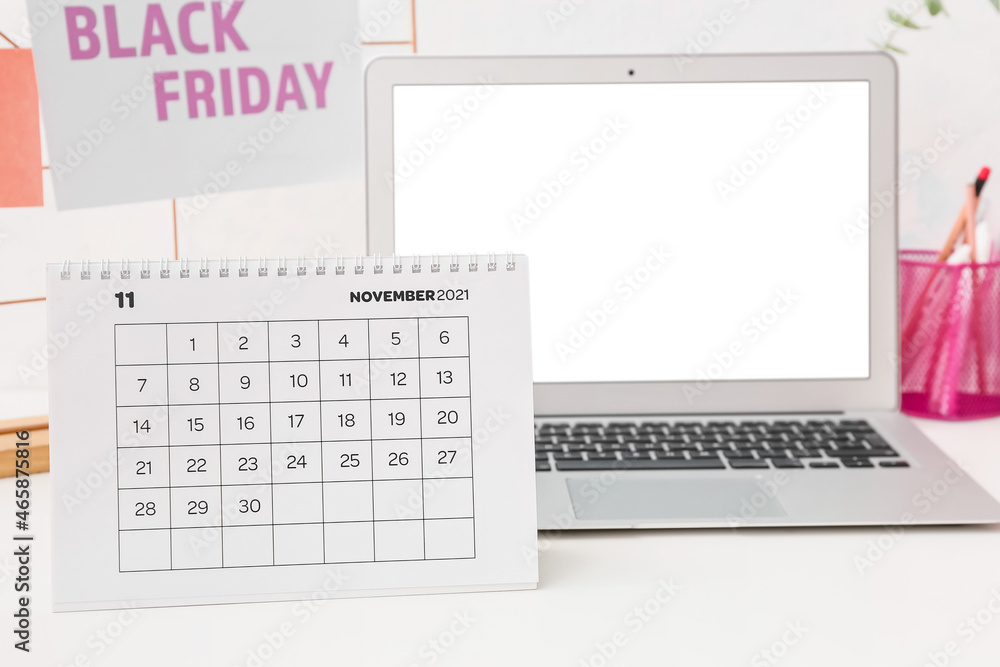 Calendar page of November 2021 and laptop on table. Black Friday Calendar page of November 2021 and laptop on table. Black Friday