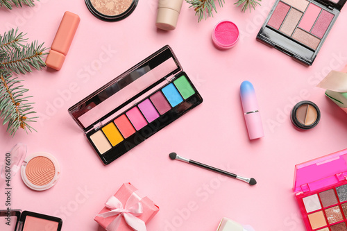 Makeup cosmetics with fir branches and gift on pink background