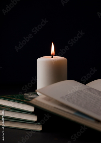 candles with flame, and reading book on desk, black background. (focus on candle).