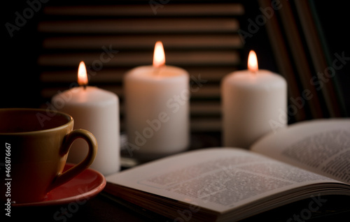 cup of tea with hot smoke and lit candle. on the desk at home, power outage (focus on cup).