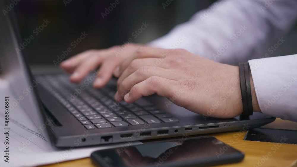 Close-up male hands typing on laptop keyboard in slow motion. Unrecognizable Caucasian man texting e-mail sitting at table with device. Wireless communication and business concept Close-up male hands typing on laptop keyboard in slow motion. Unrecognizable Caucasian man texting e-mail sitting at table with device. Wireless communication and business concept