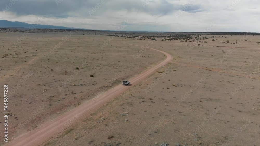 Long tracking aerial follows white jeep on dusty desert road in Utah Long tracking aerial follows white jeep on dusty desert road in Utah