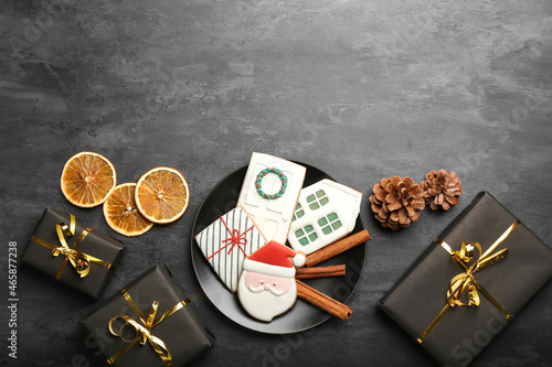 Plate with delicious Christmas cookies and gifts on dark background