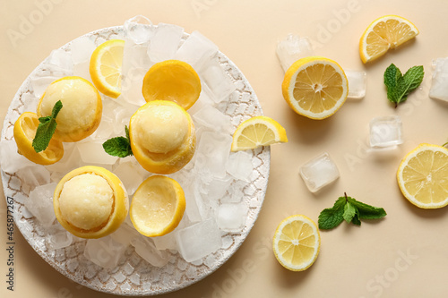 Plate with tasty ice creams in lemon peels on color background photo