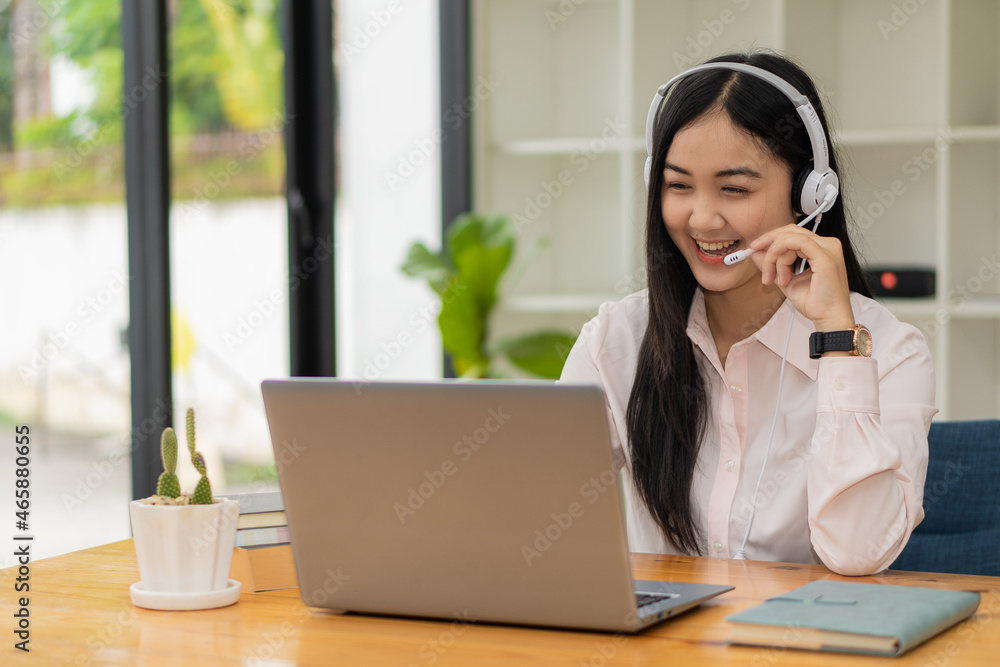 Asian female student wearing headphones for online distance learning in a virtual classroom with a tutor on a laptop by video conferencing. front view of teenage girl student with a teacher online Asian female student wearing headphones for online distance learning in a virtual classroom with a tutor on a laptop by video conferencing. front view of teenage girl student with a teacher online