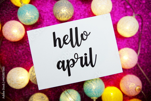Hello April text on paper card with LED cotton balls decorate on pink background © may1985