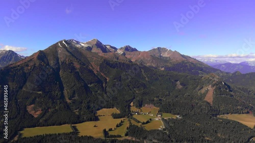 Aerial flight over alpine mountain range with small hut photo