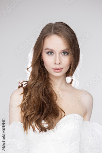 Portrait of a charming young woman in a luxurious white dress on a black background. A bride in a wedding dress, a happy smile and a portrait.