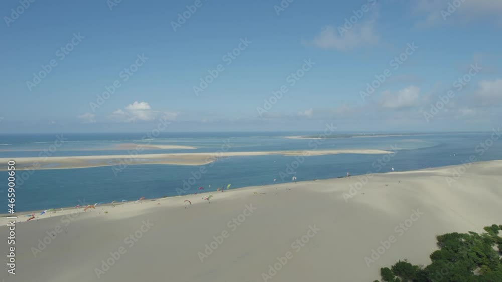 Dune of Pilat with paragliders taking flight at the top panoramic view of Arcachon Bay France, Aerial dolly left shot