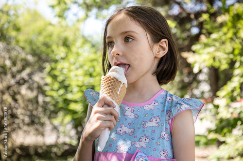 Little pretty girl eating ice cream in summer in the park on a sunny day