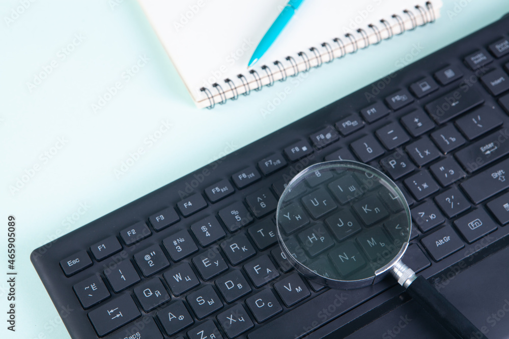 a magnifying glass on the keyboard and a notepad next to it a magnifying glass on the keyboard and a notepad next to it