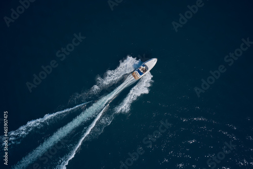 White speed boat fast movement on the water top view. Travel - image. Diagonal boat movement on blue water top view. Top view of a white high-speed boat.