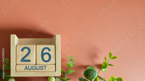 August 26, Date design with calendar cube and leaf on orange background.