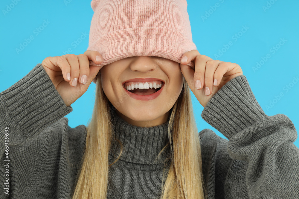 Attractive girl in sweater and knitted cap on blue background Attractive girl in sweater and knitted cap on blue background