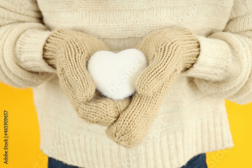Girl holds decorative snow heart on yellow background