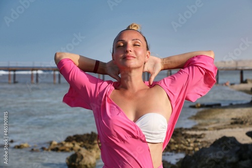 A girl in a swimsuit on the seashore expresses the emotions of pleasure.