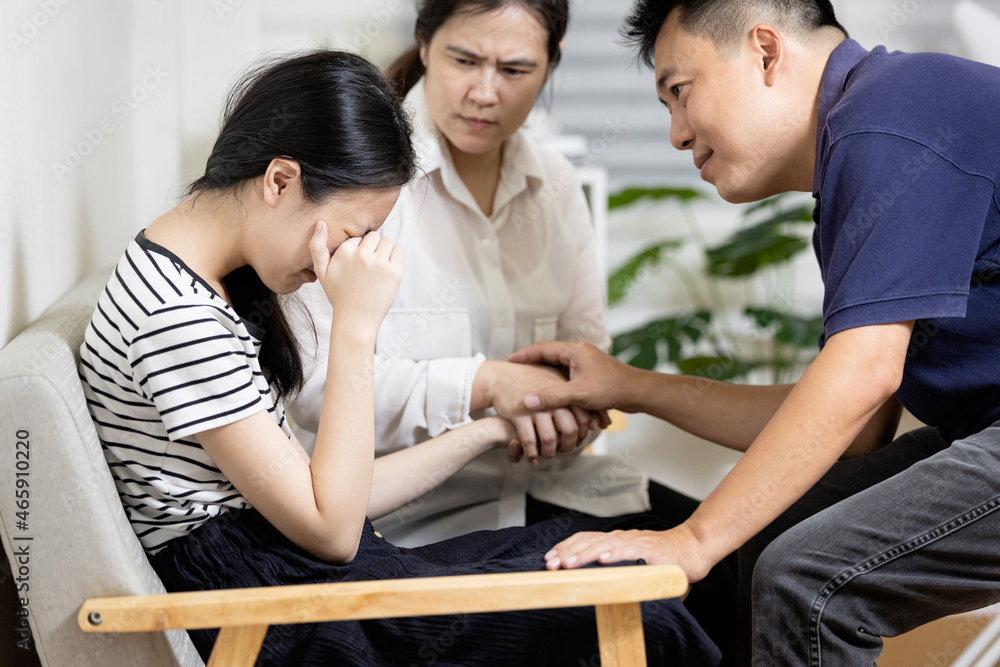 Asian parents give advice,talk sharing thoughts care to teenage girl,mom and dad holding hands to comfort and consoling daughter together,sad teenager student crying at home,family life relationship Asian parents give advice,talk sharing thoughts care to teenage girl,mom and dad holding hands to comfort and consoling daughter together,sad teenager student crying at home,family life relationship