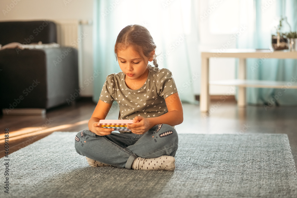 A little girl holds a phone with a case pop-it in her hands A little girl holds a phone with a case pop-it in her hands
