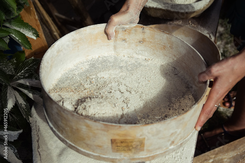 Hands holding a traditional sieve with some flour in it. Old milling process. 
