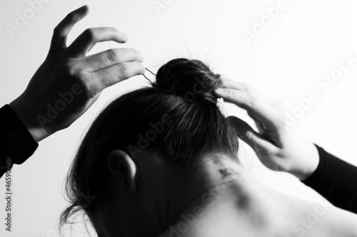 A woman stabs her hair and collects it in a bun. Black and white photo. Photo from the back. photo