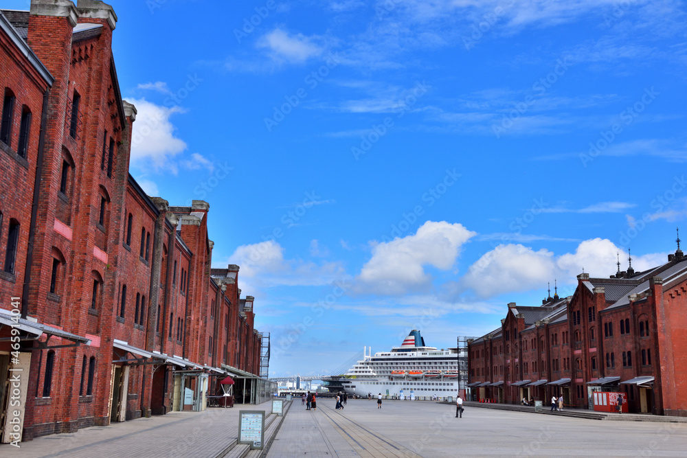 Obraz premium 青空に浮かぶ白い雲と赤レンガ倉庫と豪華客船