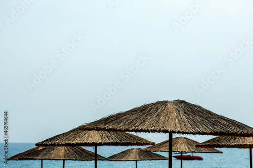 Large straw umbrellas on the beach against the background of the sea and sky. © kpn1968