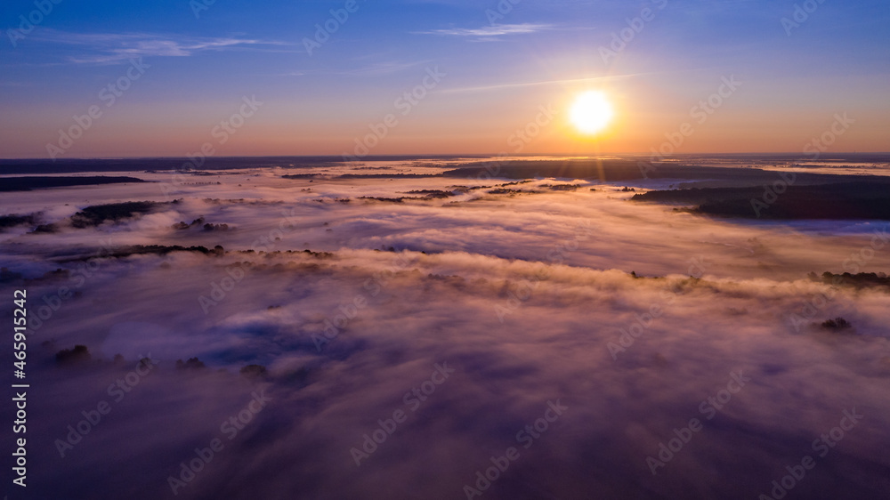 Aerial  view of a beautiful summer  landscape with a fog while dawn.  Photo from drone of a foggy landscape in spring. Top view to land while sunrise. Sun is above the horizon