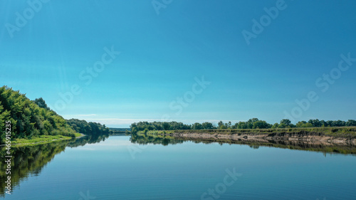 Aerial view of a beautiful summer landscape over river while dawn. Top view over river with a smooth water surface reflecting blue sky. © Valua Vitaly