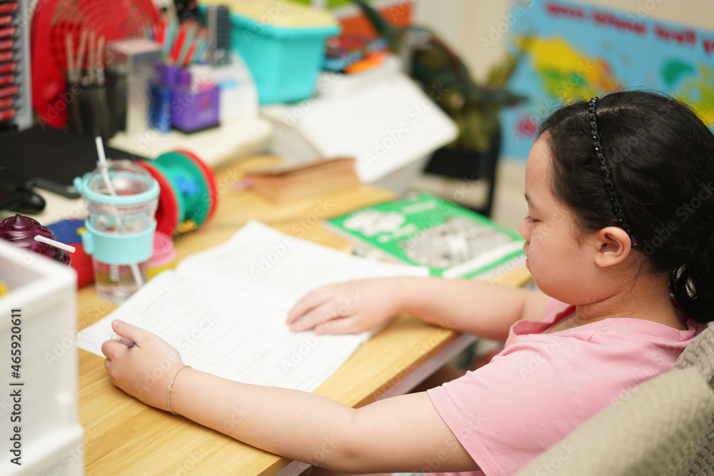 asian Child sit and writing book on table in room house,learn at home school in covid 19 quarantine asian Child sit and writing book on table in room house,learn at home school in covid 19 quarantine