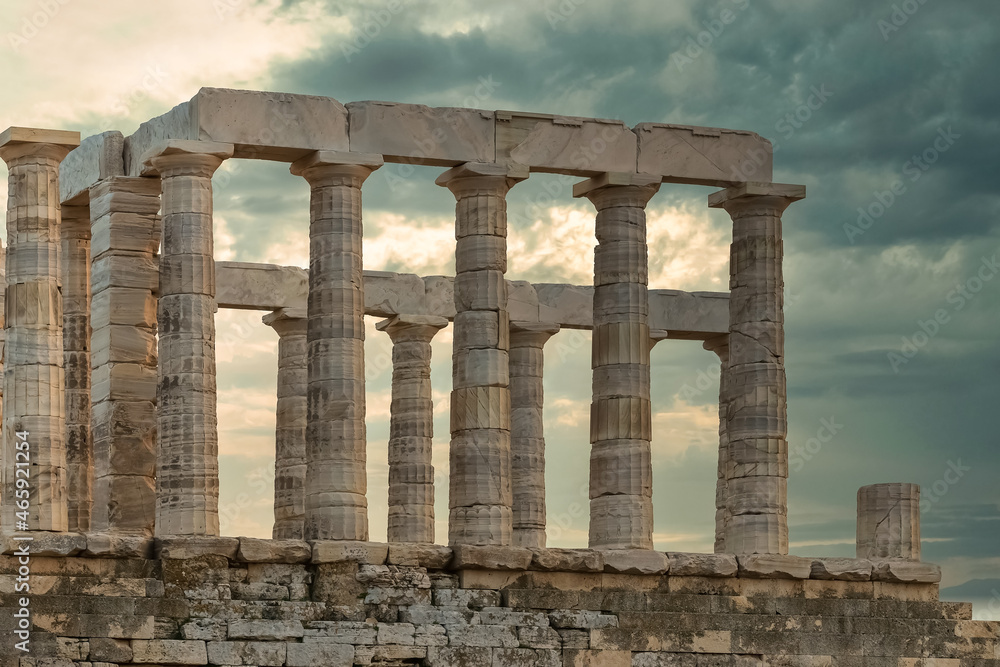 Temple of Poseidon in Greece against a dramatic sky. 
