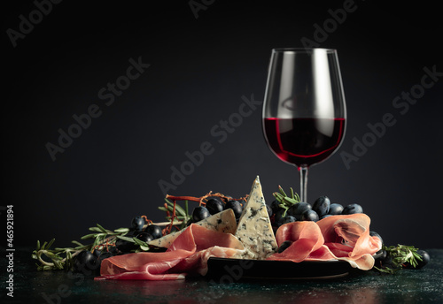 Valokuva Red wine with grapes, rosemary, prosciutto, and blue cheese.