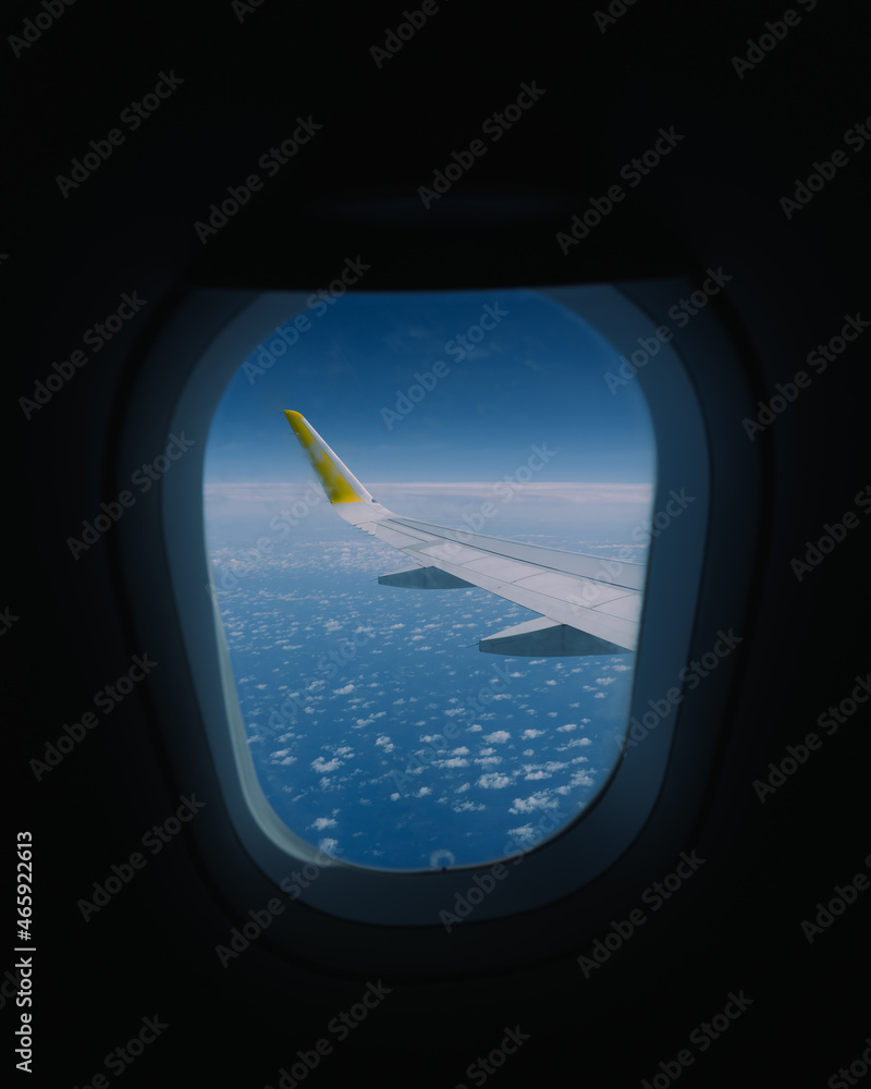 Vue d'un hublot sur l'aile de l'avion, au dessus de la mer ou de l'océan bleu avec des nuages. Vue d'un hublot sur l'aile de l'avion, au dessus de la mer ou de l'océan bleu avec des nuages.