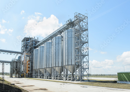 Modern commercial grain or seed silos in rural landscape. Metal grain elevator in agricultural zone