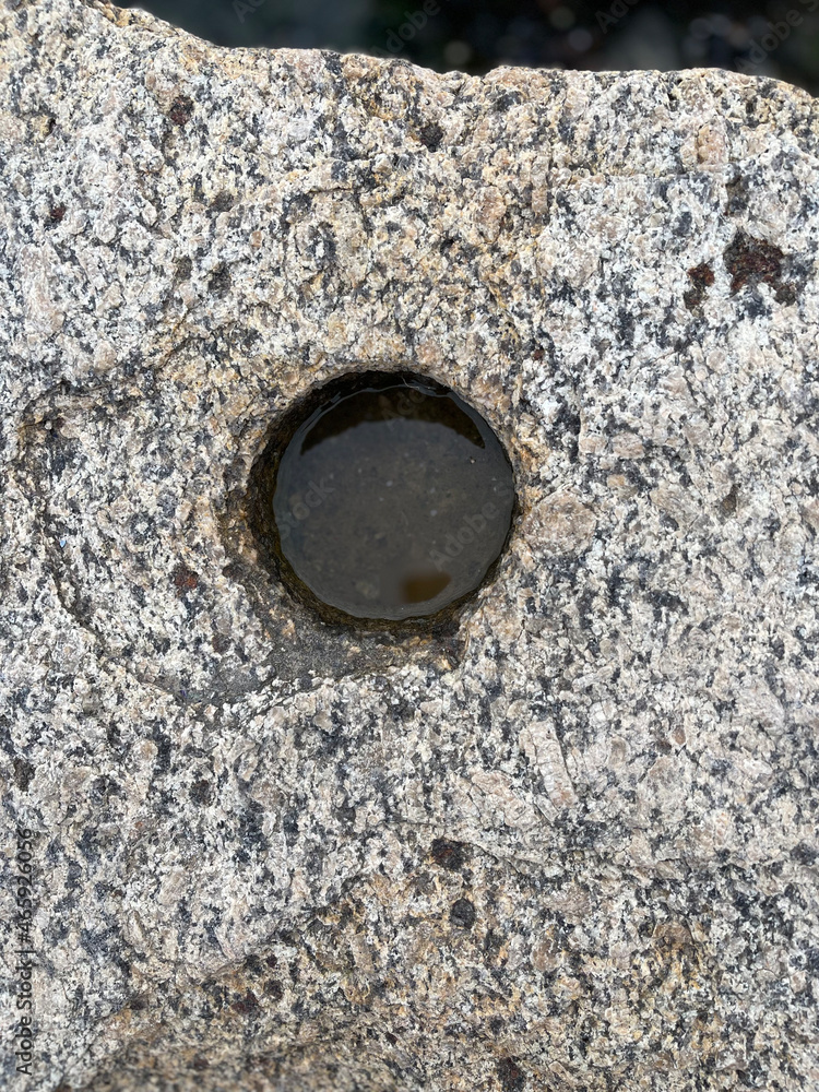 Technological Round hole in granite stone filled with rainwater Technological Round hole in granite stone filled with rainwater